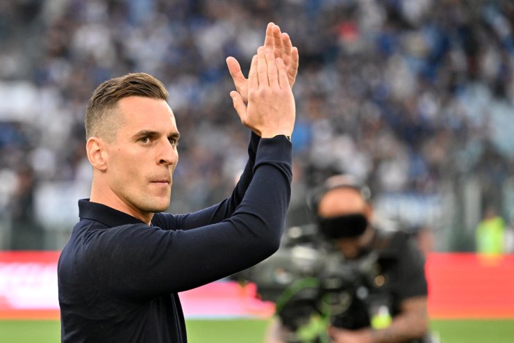 Milik applaude con indosso abiti borghesi