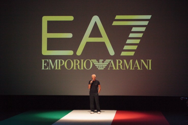 Armani durante una conferenza con alle spalle il marchio EA7