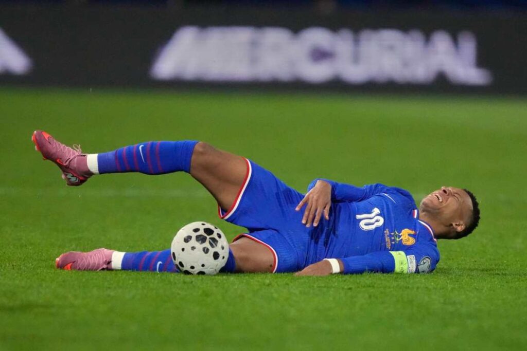 Mbappé disteso dolorante sul terreno di gioco con indosso la maglia della Francia